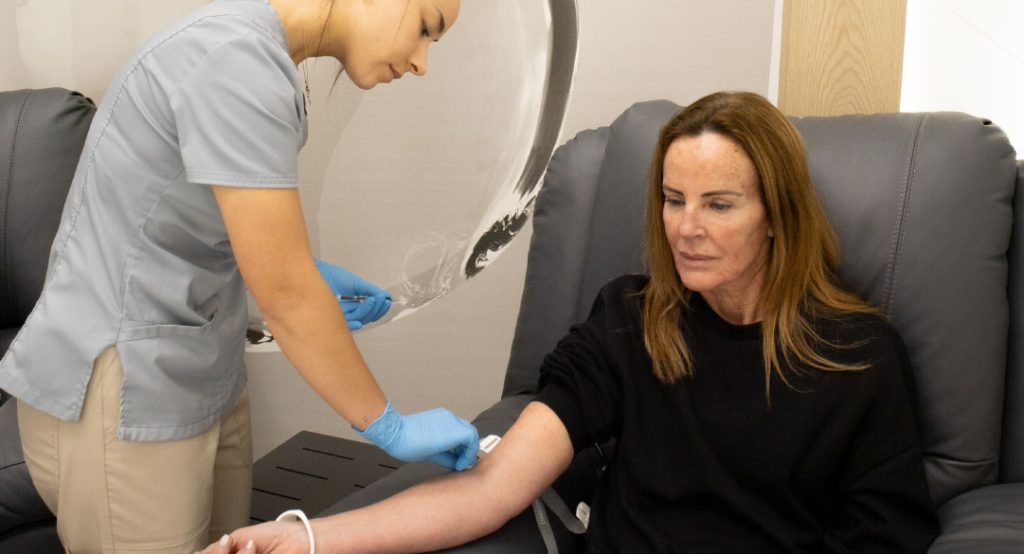Mujer recibiendo terapia endovenosa en clínica, mostrando el uso de drips con vitaminas y antioxidantes para energía y bienestar.