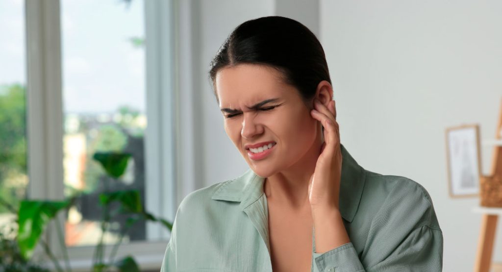 Mujer con tinnitus mostrando molestias auditivas relacionadas al sistema nervioso